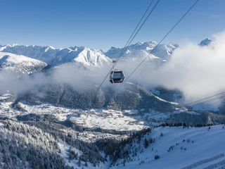 Gondelfahrt über das winterliche Fiesch Einzelfahrten Aletsch Arena mit Gondel über verschneiten Wäldern und Blick auf das Dorf Fiesch und die Walliser Alpen