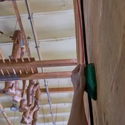 Indoor Hochseilgarten Kanuaktivtours Hand hält grünen Griff beim Klettern an einer Holzwand im Hintergrund Klettergeräte an der Decke.