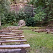 Waldbühne Leupoldishain Freiluftbühne im Wald mit hölzernen Sitzbänken und einer Felswand im Hintergrund.