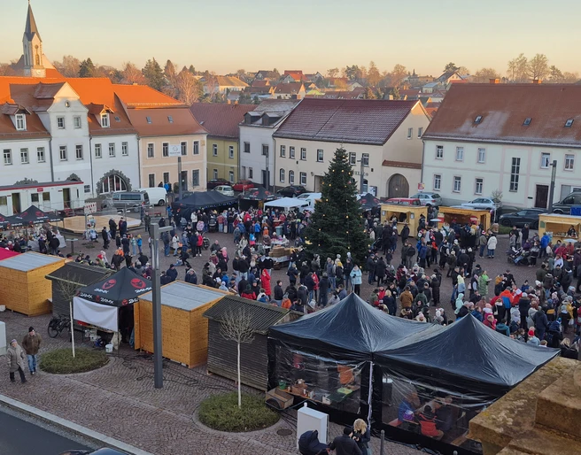 Weihnachtsmarkt Dahlen - Weihnachten in der Region Leipzig Der belebte Weihnachtsmarkt in Dahlen, umgeben von historischen Gebäuden und geschmückten Ständen.