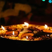 Eine runde Schale mit brennenden Kerzen. Lichter leuchten im Hintergrund.
