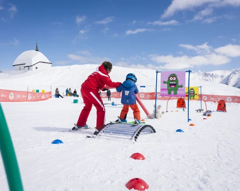 Erste Skierlebnisse auf der Bettmeralp Ski Schnupperkurs Bettmeralp mit Skilehrerin und Kind im Kinderland unter blauem Himmel und schneebedeckten Bergen
