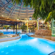 AQUALAND - wellness and aquapark Lichtdurchflutetes Freizeitbad mit tropischen Pflanzen und entspannter Wasserlandschaft.Light-flooded leisure pool with tropical plants and relaxing water landscape.