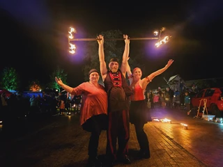 Feuerkünstler 2023 Drei Artistinnen und Artisten bei einer nächtlichen Feuershow, umgeben von zuschauender Menschenmenge.