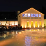 Roetgen Therme (c) Roetgen Therme.jpg Außenansicht der Roetgen Therme bei Nacht mit beleuchteten Gebäuden und einem Poolbereich.