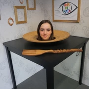 Die INSPIRATA - Optische Täuschung Der Kopf einer jungen Frau liegt in einer optischen Täuschung in der INSPIRATA scheinbar auf einem Teller auf einem Tisch