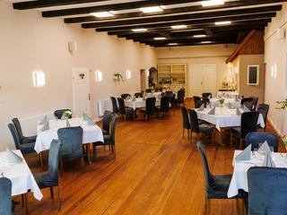 Innenansicht Saal Patchwork Köthel.jpg Innenansicht Saal Patchwork Köthel mit Tischen, Stühlen, Holzfußboden und Deckenbalken.