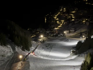 Beleuchtete Abfahrt oberhalb der Riederalp bei Nacht Beim Nachtskifahren Bettmeralp Riederalp leuchten die Skipisten oberhalb des Dorfes hell auf und bilden einen faszinierenden Kontrast zur dunklen Berglandschaft