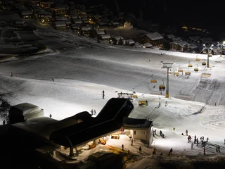 Panorama of the slopes during night skiing in the Aletsch Arena Das Nachtskifahren Bettmeralp Riederalp zeigt beleuchtete Pisten, Sessellifte und Skifahrer im Winterparadies der Aletsch Arena unter klarem SternenhimmelNight skiing Bettmeralp Riederalp shows illuminated pistes, chairlifts and skiers in the winter paradise of the Aletsch Arena under a clear starry skyLe ski nocturne Bettmeralp Riederalp montre les pistes éclairées, les télésièges et les skieurs dans le paradis hivernal de l'Aletsch Arena sous un ciel étoilé.