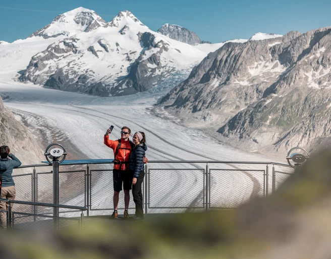 Selfie avec vue au View Point Eggishorn Das View Point Package Aletsch zeigt ein Paar beim Selfie auf dem Eggishorn mit spektakulärer Aussicht auf den Grossen AletschgletscherThe View Point Package Aletsch shows a couple taking a selfie on the Eggishorn with spectacular views of the Great Aletsch GlacierLe forfait View Point Aletsch montre un couple en train de prendre un selfie sur l'Eggishorn avec une vue spectaculaire sur le grand glacier d'Aletsch.