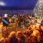 Winterland Erwachen Winterliches Zelt mit leuchtenden Lichtern, festliche Atmosphäre und Menschen in wärmender Kleidung versammelt.Wintery tent with glowing lights, festive atmosphere and people gathered in warm clothing.