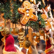 Destination Kalenderbilder(1).jpg Lebkuchen, Nussknacker und goldene Nüsse hängen an grünen Zweigen mit warmem Licht.