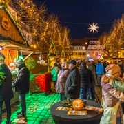 Weihnachtsmarkt Döbeln - Weihnachten in der Region Leipzig  Der Weihnachtsmarkt in Döbeln zeigt eine stimmungsvolle Szenerie mit leuchtenden Lichtern und fröhlichen Menschen, die die festlich geschmückten Holzbuden erkunden. Die warme Beleuchtung und der Sternenhimmel schaffen eine einladende Atmosphäre, während Besucher in Winterkleidung zwischen den Ständen flanieren.