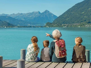 Grandmother sitting with children on the jetty in Iseltwald