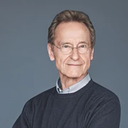 Literatur zur Nacht_Bernhard Schlink (c) Gaby Gerster Diogenes Verlag.jpg Schriftsteller Bernhard Schlink vor grauem Hintergrund, lächelnd, trägt Hemd und Pullover.