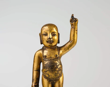 The newborn Buddha Goldene Buddha-Statue, die auf einer Lotusblüte stehend, einen Arm erhebt.Golden Buddha statue standing on a lotus blossom, raising one arm.