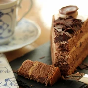 Schokoladenkuchen mit Streuseln und eine Kaffee auf einer Untertasse links daneben.