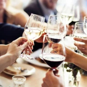 Weinbar Mehrere Personen stoßen mit Weingläsern an.