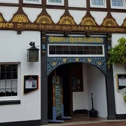 Schweers Harms Fischerhus Fachwerkhaus mit traditionellen Verzierungen und Rankpflanzen am Eingang; Schild: "Schweers Harms Fischerhus".