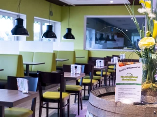 Fischfeinkost Lindemann Restaurant I Ein modern gestaltetes Restaurant mit hellen, grünen Sitzbänken und einem Blumenarrangement.