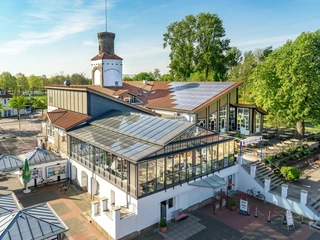 Strandterrassen aus Richtung Norden Wntergarten Wintergarten eines großen Gebäudekomplexes, umgeben von Bäumen, mit Fahrradständern im Vordergrund.