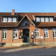 Hotel & Restaurant Alte Schule Ein Backsteingebäude mit hohen Fenstern und Schildern über dem Eingang unter einem Giebeldach.