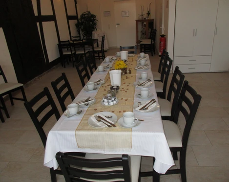 Kaffeerösterei Koboldt I Ein langer Tisch in einem Café ist festlich mit weißem Tischtuch, Geschirr und Dekoration gedeckt.