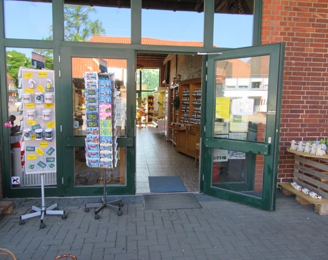 Eingang-Hofladen-Niemeyer Der Eingangsbereich eines Hofladens mit offenen Türen, innen sind Regale mit Produkten zu sehen.