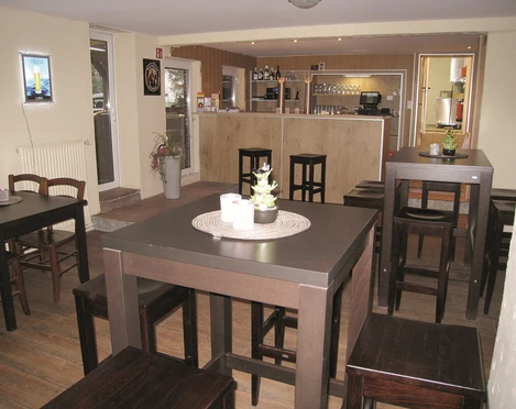 Thekenbereich Der Thekenbereich in einem gemütlichen Lokal, mit Holzstühlen und kleinen Pflanzen dekoriert.