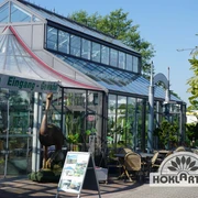 Orangerie Außenansicht Die Orangerie zeigt eine moderne, gläserne Fassade mit Pflanzen im Eingangsbereich.