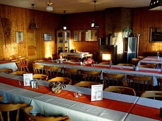 Gastraum in der Luisenturmhütte Borgholzhausen Ein rustikaler Gastraum mit Holzmobiliar und dekorativem Kamin, geschmückt mit roten Tischläufern.