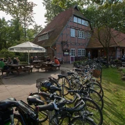 gasthaus-zum-heidemuseum-mit-terrassen Historisches Fachwerkhaus mit sonniger Terrasse und Fahrrädern im Vordergrund vor bewaldeter Kulisse.