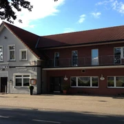 Köhncke's Hotel Das Foto zeigt Köhncke's Hotel, ein zweistöckiges Gebäude mit grauer und roter Fassade sowie einem Satteldach.