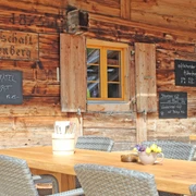 restaurant de montagne Stierenberg-terrasse avec soleil d'été Holztisch mit grauen Stühlen vor der Hauswand des GasthofsWooden table with gray chairs in front of the house wall of the innTable en bois avec chaises grises devant le mur de l'auberge