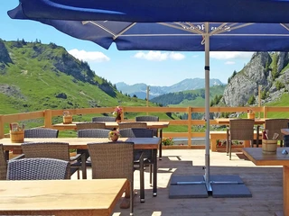 Blick von der Sommerterrasse im Berggasthaus Stierenberg  Terrasse des Bergrestaurants mit Tischen, Stühlen und Sonnenschirme, umgeben von einem HolzzaunTerrace of the mountain restaurant with tables, chairs and parasols, surrounded by a wooden fenceTerrasse du restaurant d'altitude avec tables, chaises et parasols, entourée d'une clôture en bois