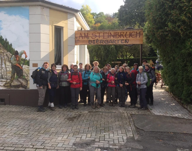 Wandergruppe vor dem Restaurant & Café Am Steinbruch in Hilter Eine Wandergruppe posiert fröhlich vor dem Restaurant & Café Am Steinbruch in Hilter im Freien.