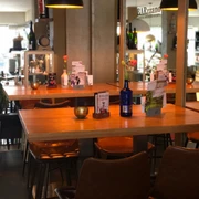 Barzzano Nienburg Modernes Café mit hölzernen Tischen, Ledersesseln und dekorativen Details in warmem Licht.