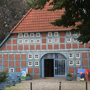 Clüverhaus Fachwerkhaus aus rotem Backstein mit blauen Holzbalken und bunten Kunstwerken auf einer grünen Wiese.