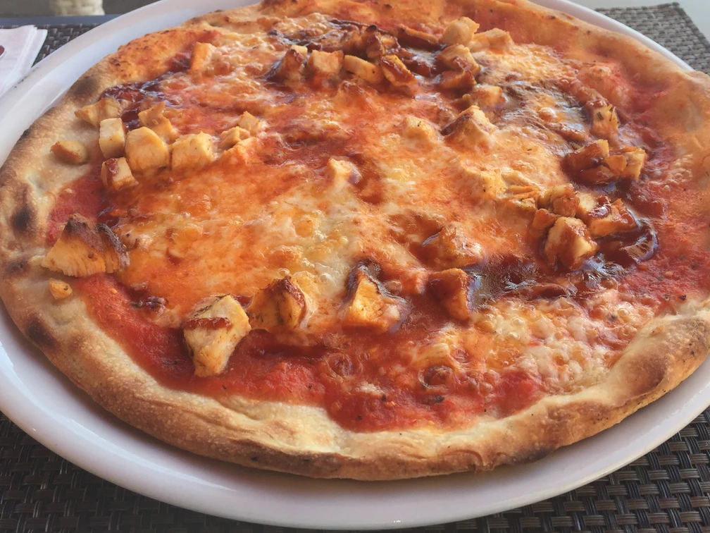 Pizza Frisch gebackene Pizza mit goldbraunem Rand, saftiger Tomatensauce und zarten Hähnchenstücken.