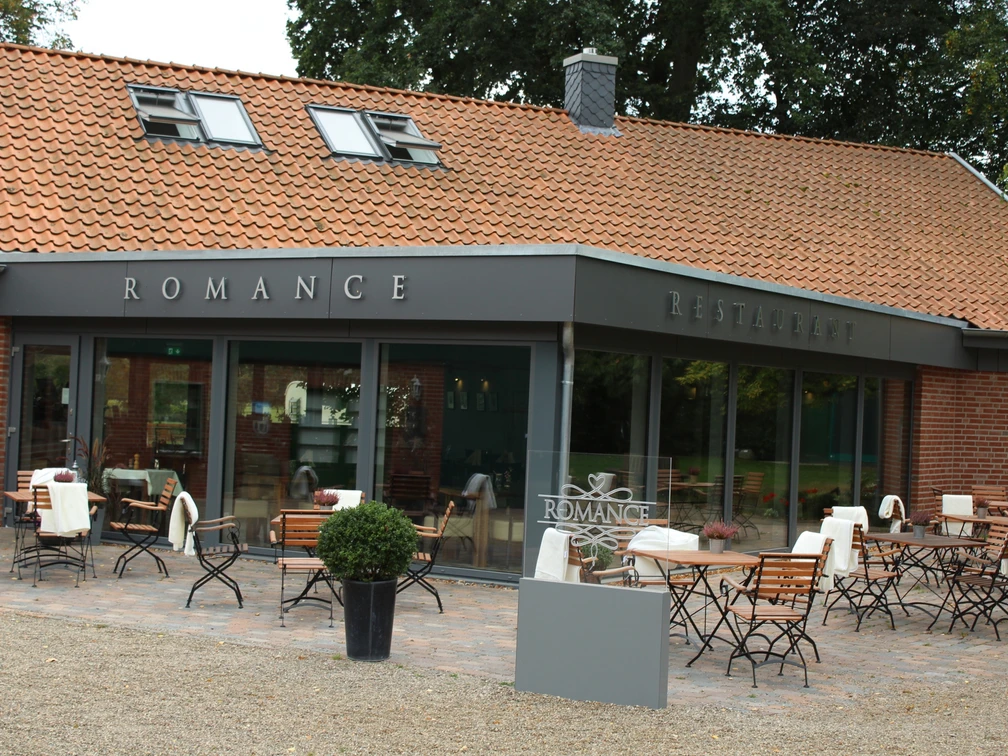 Romance Außenansicht des Restaurants "Romance" mit Terrassenbestuhlung vor einem Backsteingebäude.