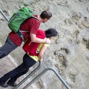 Dinosaurussporen in Bad Essen De Wittekindsweg brengt wandelaars onder meer naar de dinosaurussporen in Bad Essen-BarkhausenPersonen betrachten Spuren prähistorischer Dinosaurier in einer Felswand.