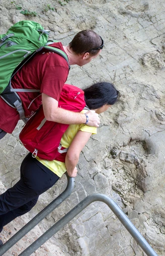 Saurierspuren in Bad Essen De Wittekindsweg brengt wandelaars onder meer naar de dinosaurussporen in Bad Essen-BarkhausenPersonen betrachten Spuren prähistorischer Dinosaurier in einer Felswand.