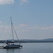 Ein Segelboot mit ruhiger Wasseroberfläche am Ufer des Steinhuder Meers unter einem klaren Himmel.