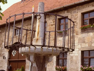 Schandpfahl vor dem Museum in Obermarsberg Schandpfahl mit metallenen Streben vor einer steinernen Fassade in Obermarsberg, Deutschland.