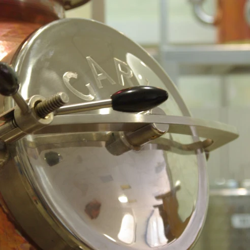 Feindestillerie GeistReich in Willebadessen Kupferner Brennkessel mit glänzendem Deckel und präzise gearbeiteter Mechanik in einer Brennerei.
