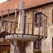 Schandpfahl-Pranger vor Marsberger Rathaus Historischer Pranger aus Stein und Metall vor einem traditionellen Gebäude mit blumengeschmückten Fenstern.