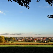 Blick auf Hilter Blick auf die Gemeinde Hilter mit Umrissen im Morgennebel, umgeben von Feldern und Bäumen im Vordergrund.