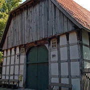 Holzhandwerksmuseum Hiddenhausen Historisches Fachwerkhaus mit großem Holztor und Ziegeldach, umgeben von Bäumen.