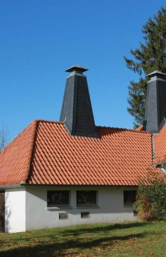 Ältestes Wasserwerk im Kreis Herford Das älteste Wasserwerk im Kreis Herford, rot gedecktes Dach, markante Schornsteine, umgeben von Grün.