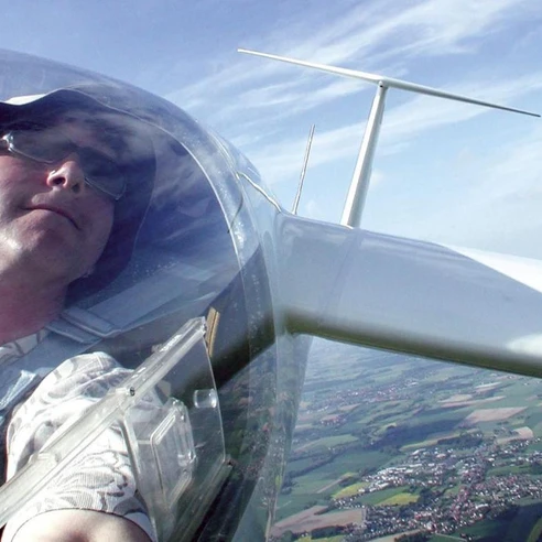 Segelflieger über Oerlinghausen Person in einem Segelflugzeug, fotografiert aus der Pilotenkabine, überblickt Felder und Landschaften.